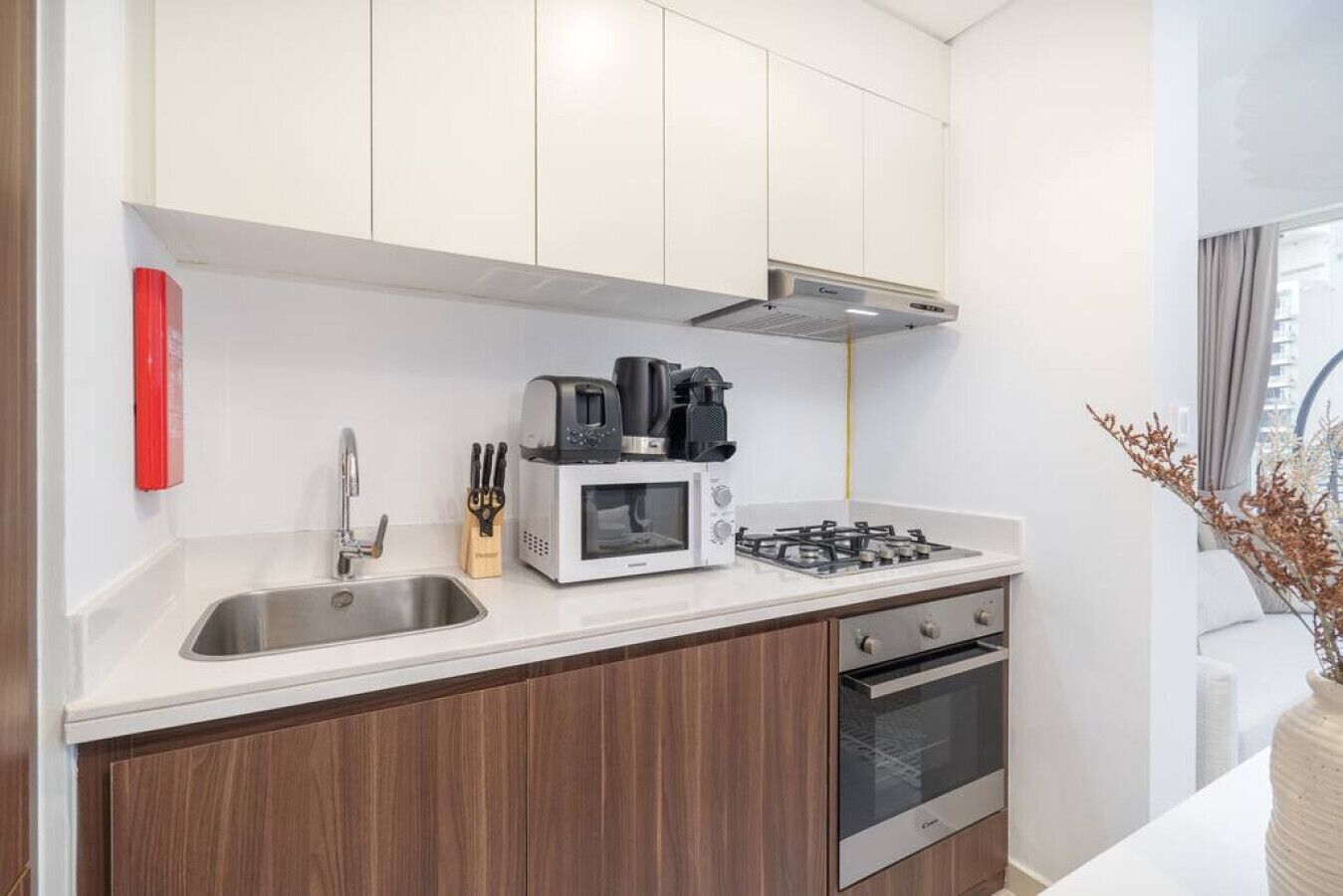 A modern kitchen with white cabinets, a stainless steel sink, a microwave, a gas stove, and a built-in oven.