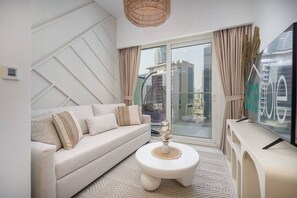 A modern living room with a sofa, a round coffee table, and a TV on a stand. - Business Bay Bliss 1 bedroom apartment - Suiteable (Dubai)