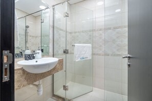 A modern bathroom with a glass shower enclosure, a white sink, and a marble countertop.
