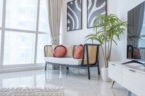 A modern living room with a sofa, cushions, a potted plant, and artwork on the wall.