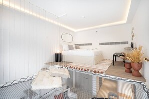 Un dormitorio moderno con cama, mesitas de noche, un escritorio y una planta en maceta.