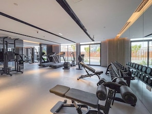 A modern gym with various exercise equipment, large windows, and a clean, spacious layout. - Fashionable loft with catamaran net in JVC (Dubai)