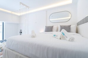 A modern hotel room with a large bed, white linens, and a large mirror above it. - Fashionable loft with catamaran net in JVC (Dubai)