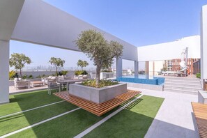 Terraza en la azotea con mobiliario exterior, piscina y vistas al horizonte de la ciudad.