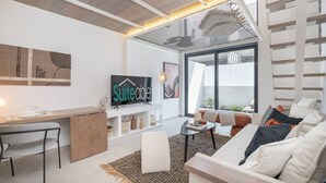 Una sala de estar moderna con un sofá, una mesa de centro, un televisor y un escritorio.