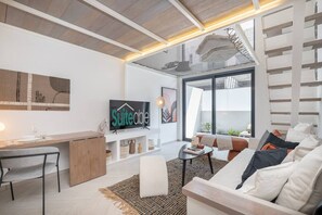 A modern living room with a sofa, a coffee table, a TV, and a desk. - Fashionable loft with catamaran net in JVC (Dubai)
