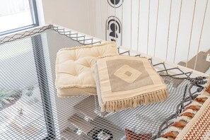 A room with a metal mesh bed frame, a tufted cream-colored pillow, and a woven throw blanket with a geometric pattern. - Fashionable loft with catamaran net in JVC (Dubai)