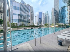 A rooftop swimming pool with a view of modern high-rise buildings.