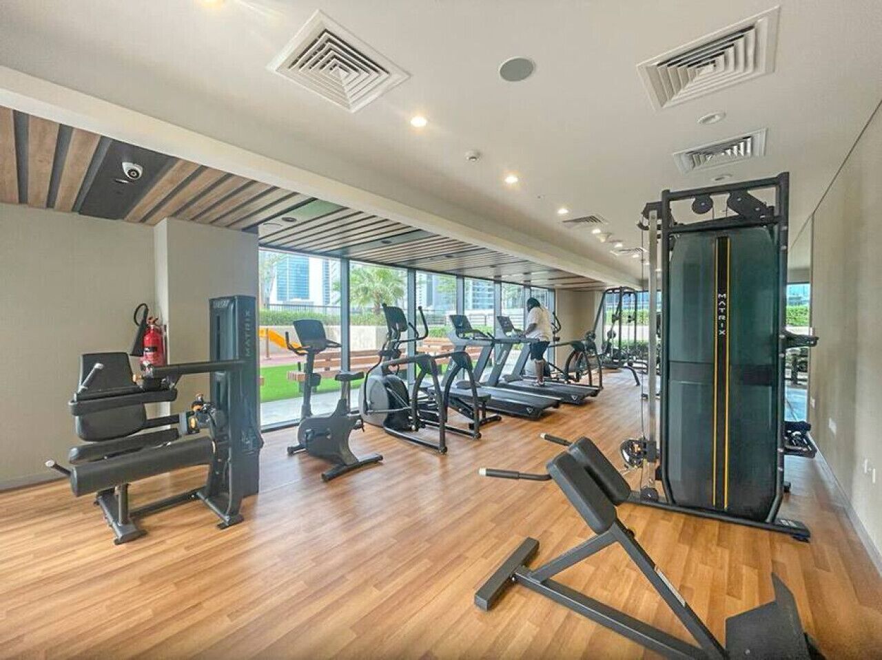 Une salle de sport équipée de tapis de course, d’appareils de musculation et d’un support pour les exercices de squat.