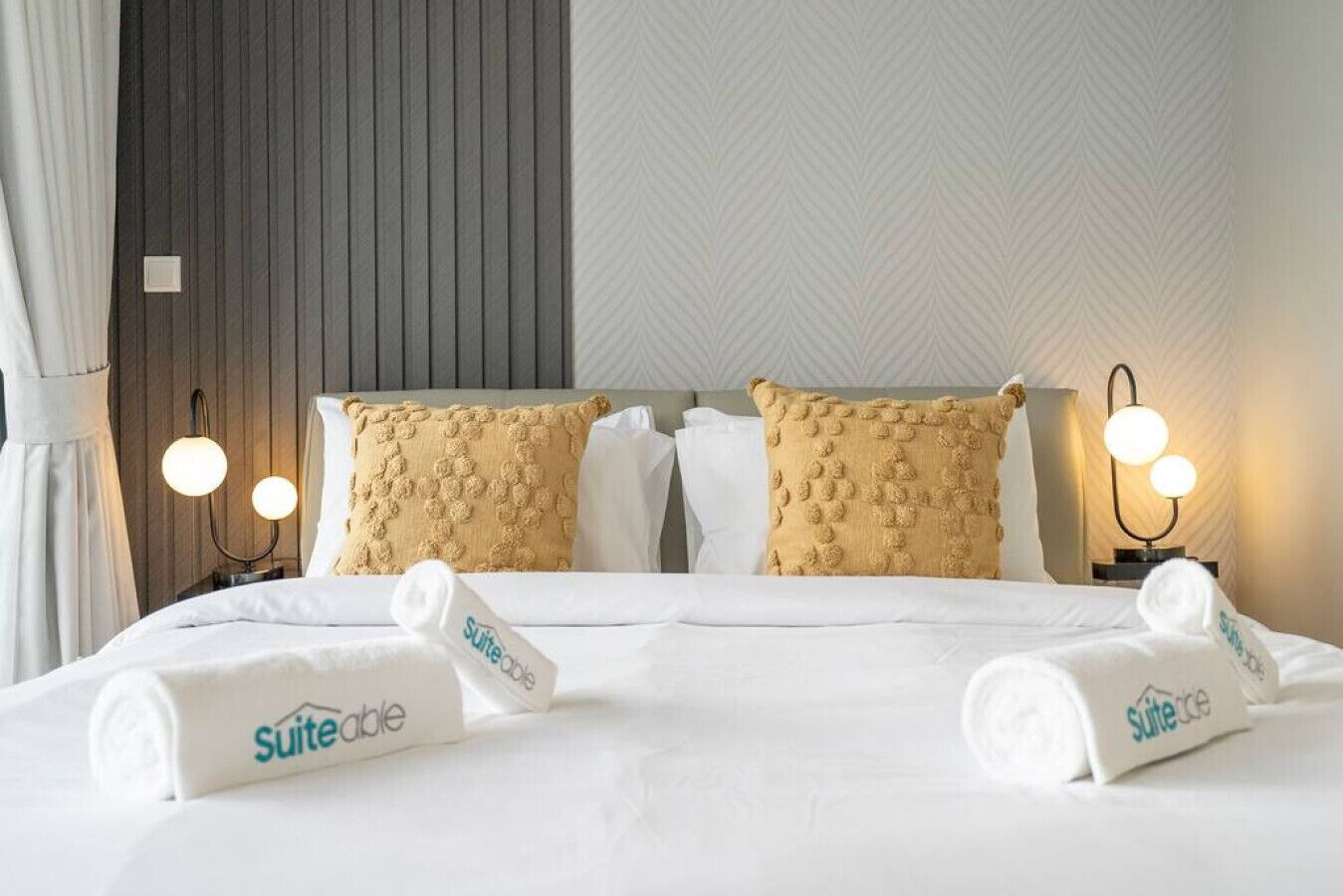 Une chambre d’hôtel avec un lit, deux oreillers, une table de chevet et une lampe.