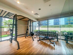 A gym with wooden flooring, weightlifting equipment, and a bench.