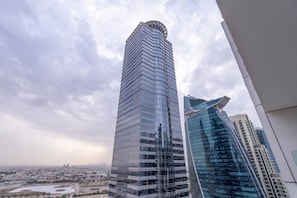 A high-rise building with a curved design, surrounded by other modern buildings and a cityscape in the background.