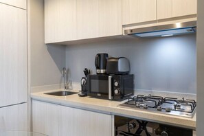 A modern kitchen with a gas stove, a coffee maker, and a microwave.