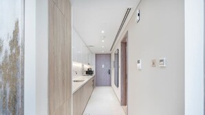 A modern hallway with a kitchen area, light-colored walls, and a minimalist design.
