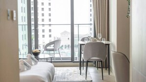 A modern hotel room with a balcony, a dining area, and a bed.