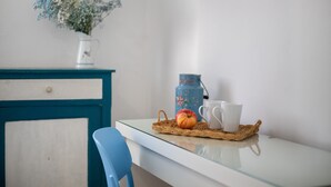 Una mesa con un posavasos tejido, una taza blanca y un jarrón azul con flores.