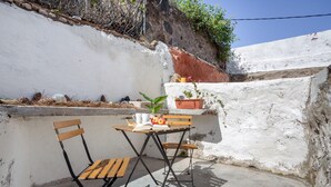 Un pequeño espacio al aire libre con una mesa, dos sillas, una planta en maceta y un libro.