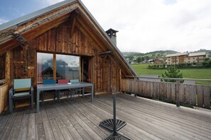A wooden cabin with a deck, a table, and chairs.