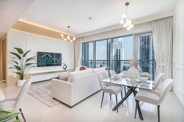 A modern living room with a white sofa, glass dining table, and a large window with a city view.