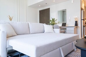 A modern living room with a sectional sofa, a desk, and a large mirror.