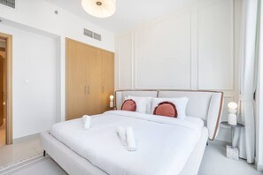 Ein modernes Hotelzimmer mit einem großen Bett, einem Holzschrank und einem kleinen Nachttisch mit Lampe.