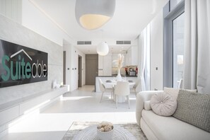 A modern hotel interior with a dining area, a living room with a sofa, and a large sign on the wall.
