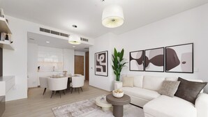 Ein modernes Wohnzimmer mit einem weißen Sofa, einem Essbereich und Kunstwerken an den Wänden.