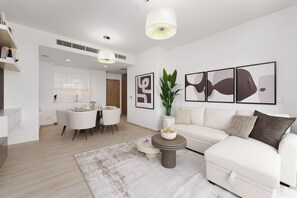 A modern living room with a white sofa, a dining area, and artwork on the walls.