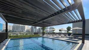 Ein Pool auf dem Dach mit Blick auf hohe Gebäude im Hintergrund.