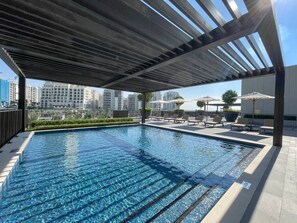 A rooftop swimming pool with a view of high-rise buildings in the background.