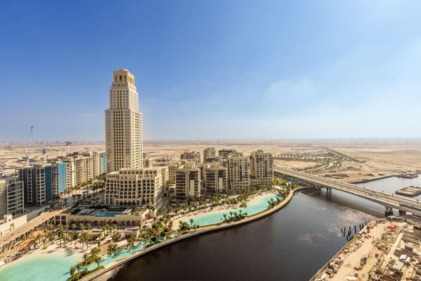 A high-rise hotel with a prominent tower, a marina, and a bridge in the background.