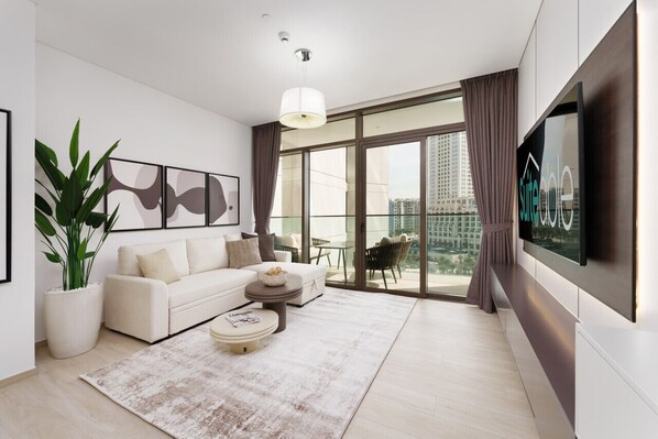 A modern living room with a sofa, coffee table, and a large TV on the wall.