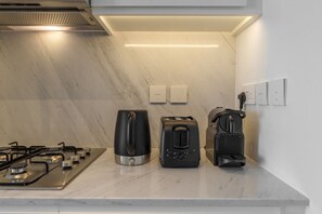 Eine Küche mit Gaskochfeld, Kaffeemaschine, Toaster und Wasserkocher auf einer Marmorarbeitsplatte.