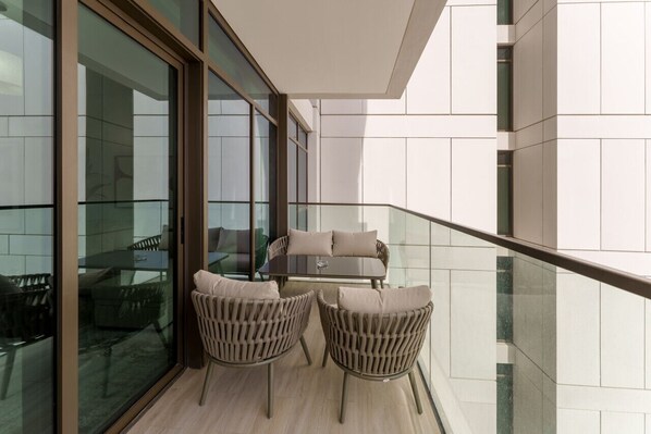 A balcony with a glass railing, a sofa, and two chairs.