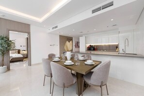 A modern dining area with a wooden table set for four, surrounded by grey chairs.