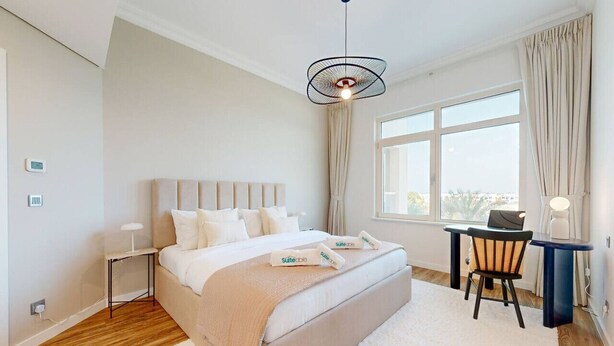 A modern bedroom with a large bed, a desk, and a chair.