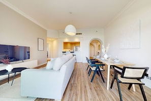 Una sala de estar moderna con un sofá, un televisor y una zona de comedor con una mesa y sillas.