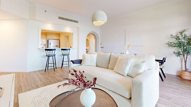 Ein modernes Wohnzimmer mit einer Couch, einem Couchtisch mit einer Vase und einem Essbereich mit Stühlen und einem Tisch.