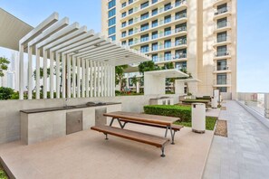An outdoor patio area with a pergola, a long bench, and a small table.