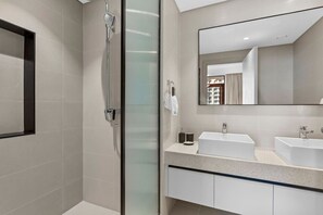 A modern bathroom with a glass-enclosed shower, two sinks, and a large mirror.