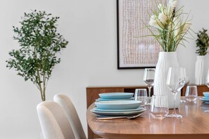 A dining table set with blue plates, clear wine glasses, and a white vase with flowers. - Luxurious Living in the heart of Emaar Beachfront (Dubai)