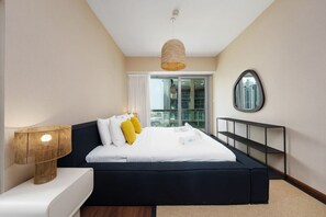 Quarto moderno com cama, mesa de cabeceira, abajur e vista para a cidade através de uma janela.