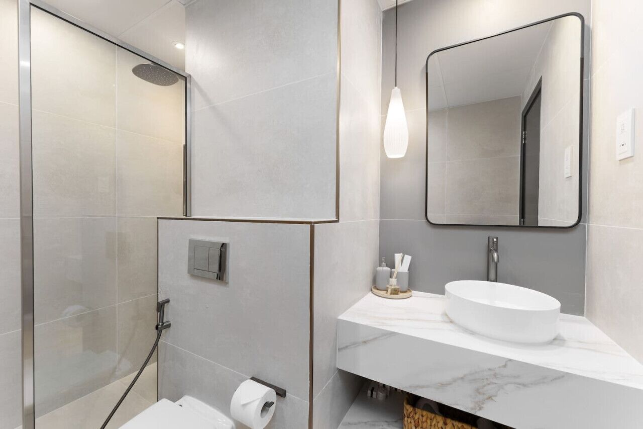 Un bagno moderno con cabina doccia in vetro, lavabo in marmo e uno specchio grande.