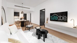 Un salon moderne avec un canapé, un coin repas et une cuisine en arrière-plan. Un panneau indiquant « suite disponible » est affiché sur le mur.