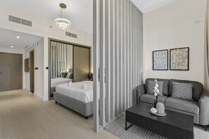 A modern hotel room with a bed, a sofa, a coffee table, and a large mirror.