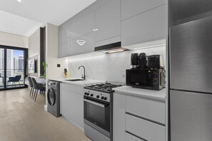 A modern kitchen with stainless steel appliances, a built-in oven, and a coffee maker. - Studio Retreat with Canal and Burj Khalifa Views (Dubai)