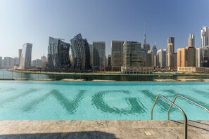 A modern cityscape with high-rise buildings, a waterfront, and a swimming pool.