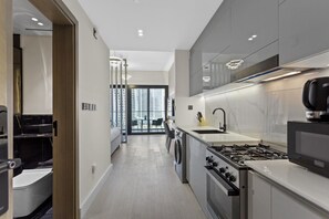 A modern kitchen with a gas stove, microwave, and a dining area with a table and chairs. - Studio Retreat with Canal and Burj Khalifa Views (Dubai)
