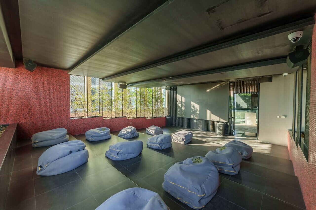Um interior moderno com almofadas de chão, escada e janelas amplas.