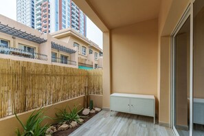 A balcony with a bamboo fence, a white storage unit, and a cactus plant. - Extraordinary Loft Living in JVC by Suiteable (Dubai)